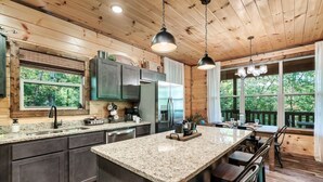 Une cuisine moderne dotée de plans de travail en granit, d’appareils électroménagers en acier inoxydable et de meubles en bois.