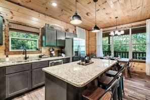 A modern kitchen with granite countertops, stainless steel appliances, and wooden cabinetry. - New! 3BR w/Hot Tub*Game Room*Fireplace*Privacy! (Pigeon Forge)