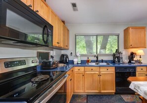 A compact kitchen with wooden cabinets, a stove, a microwave, and a dishwasher. - 2BR w/Treehouse! Hot Tub*Arcade*Fireplace*Privacy! (Sevierville)