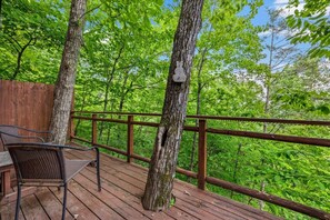 A wooden deck with a metal railing, surrounded by trees and a clear sky. - 2BR w/Treehouse! Hot Tub*Arcade*Fireplace*Privacy! (Sevierville)