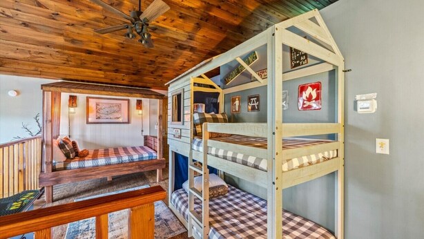 Een chalet met een stapelbed, houten plafond en een klein balkon.