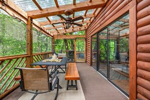 A wooden deck with a table and chairs, a hammock, and a ceiling fan. - 2BR w/Treehouse! Hot Tub*Arcade*Fireplace*Privacy! (Sevierville)
