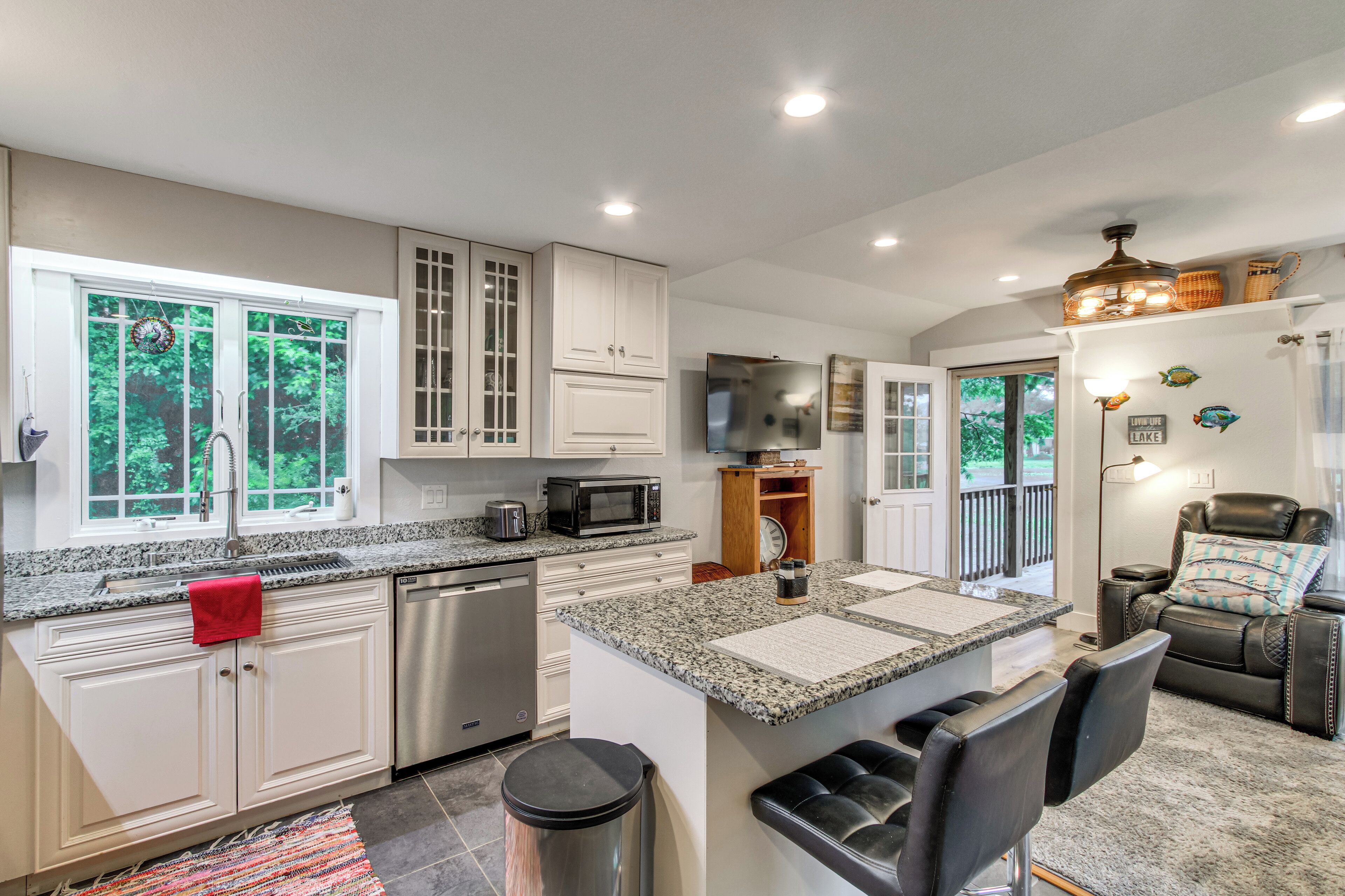 A modern kitchen with granite countertops, stainless steel appliances, and a dining area with a leather sofa and a fireplace.