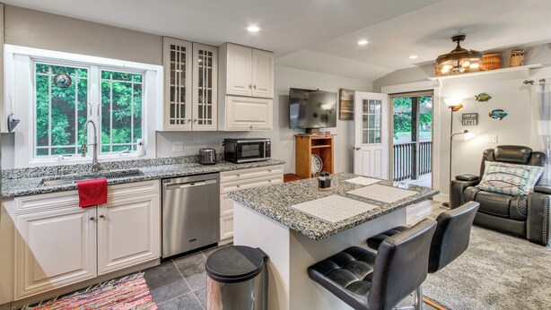 A modern kitchen with granite countertops, stainless steel appliances, and a dining area with a leather sofa and a fireplace. - Waterfront Couples Retreat w/ Views in Andalusia! (Andalusia)