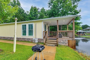 A house with a covered porch, a small staircase leading to the entrance, and a water feature in the background. - Waterfront Couples Retreat w/ Views in Andalusia! (Andalusia)