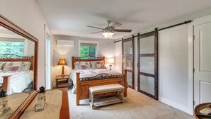 A bedroom with a bed, bench, bedside table, lamp, ceiling fan, and a large mirror. - Waterfront Couples Retreat w/ Views in Andalusia! (Andalusia)