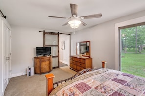 A bedroom with a bed, a ceiling fan, a dresser, a television, and a large window. - Waterfront Couples Retreat w/ Views in Andalusia! (Andalusia)