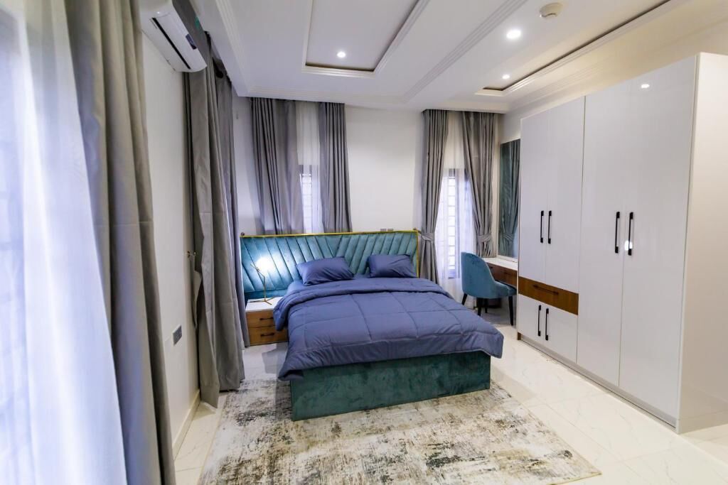 A bedroom with a bed, nightstands, a desk, a chair, and a wardrobe.