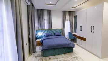 A bedroom with a bed, nightstands, a desk, a chair, and a wardrobe.