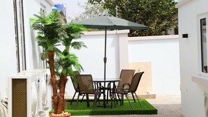 A patio with a table and chairs, a potted plant, and an umbrella. - Mind Your Business Villa (Masaka)