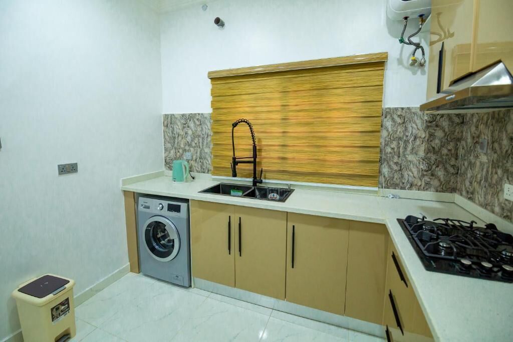 A compact kitchen with a washing machine, a sink, and a stove.
