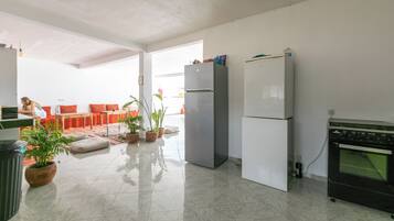 A modern kitchen with a refrigerator, oven, and potted plants.