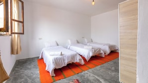 A hotel room with two beds, a red and green striped rug, a wooden wardrobe, and a hanging light fixture. - Hakuna Matata Guest House (TAMRAGHT)