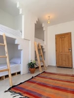 Una habitación con literas, una puerta de madera y un tapete a rayas.