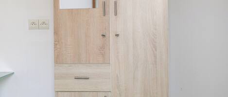 A tall wooden wardrobe with a mirror, a drawer, and a cabinet.
