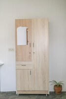 Un armario alto de madera con espejo, un cajón y un compartimento.