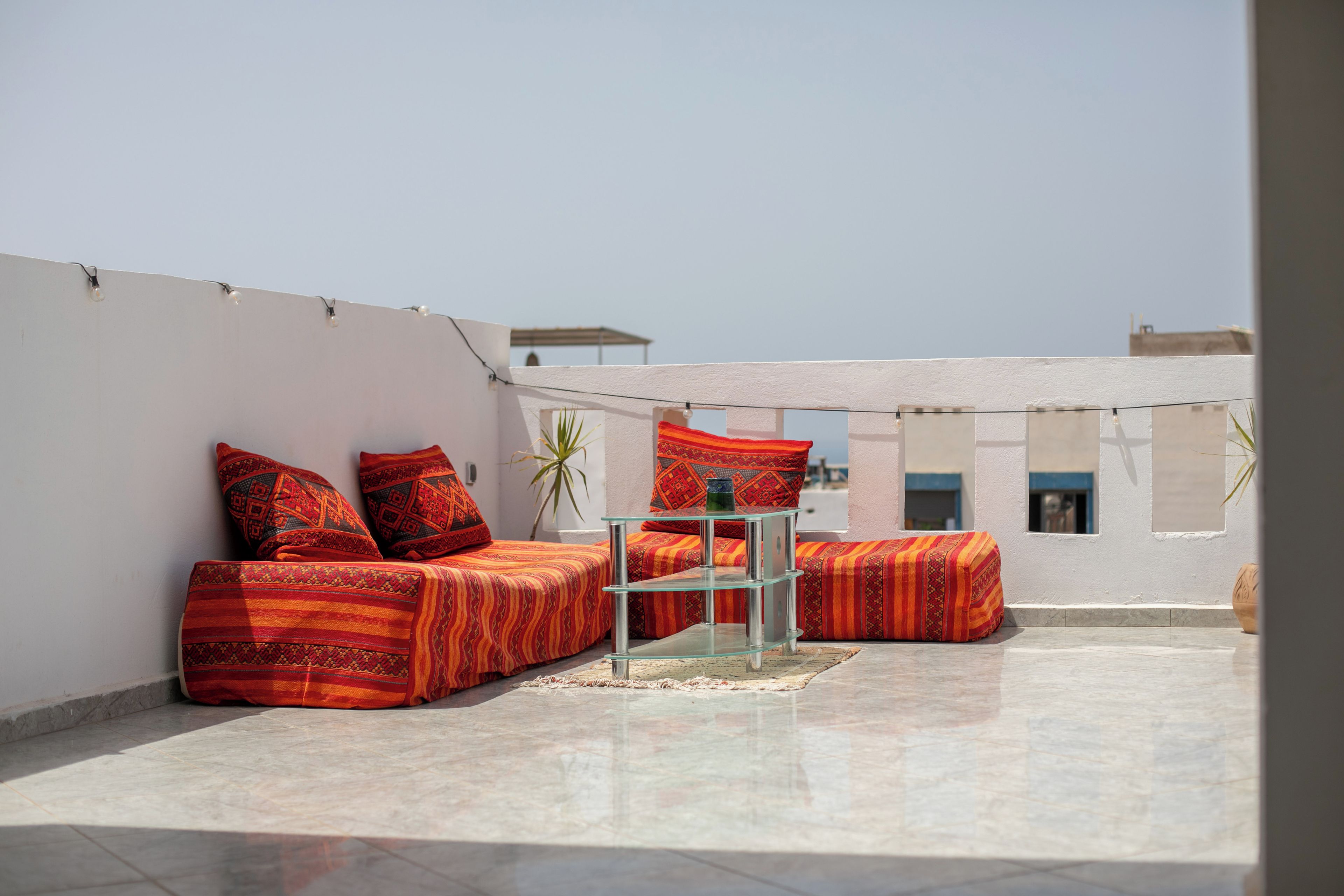 Una terraza en la azotea con un conjunto de sofás y una mesa de vidrio.
