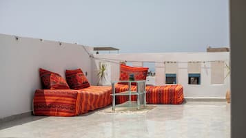 Una terraza en la azotea con un conjunto de sofás y una mesa de vidrio.