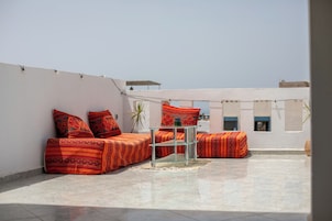 Una terraza en la azotea con un conjunto de sofás y una mesa de vidrio.