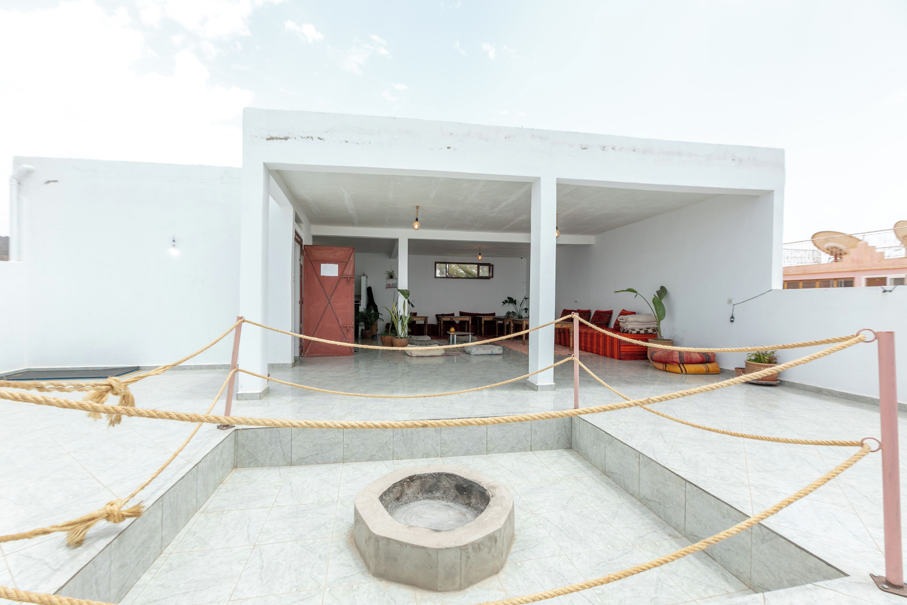 Un edificio moderno con un patio central, un área de descanso con cojines y una barrera de cuerda.