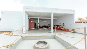 Un edificio moderno con un patio central, un área de descanso con cojines y una barrera de cuerda.