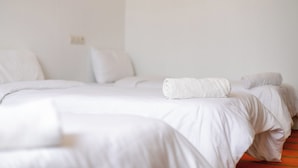 A hotel room with two beds, a white color scheme, and a visible power outlet on the wall. - Hakuna Matata Guest House (TAMRAGHT)