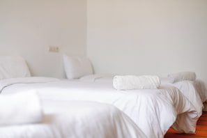 Ein Hotelzimmer mit zwei Betten, einer weißen Farbgestaltung und einer sichtbaren Steckdose an der Wand.