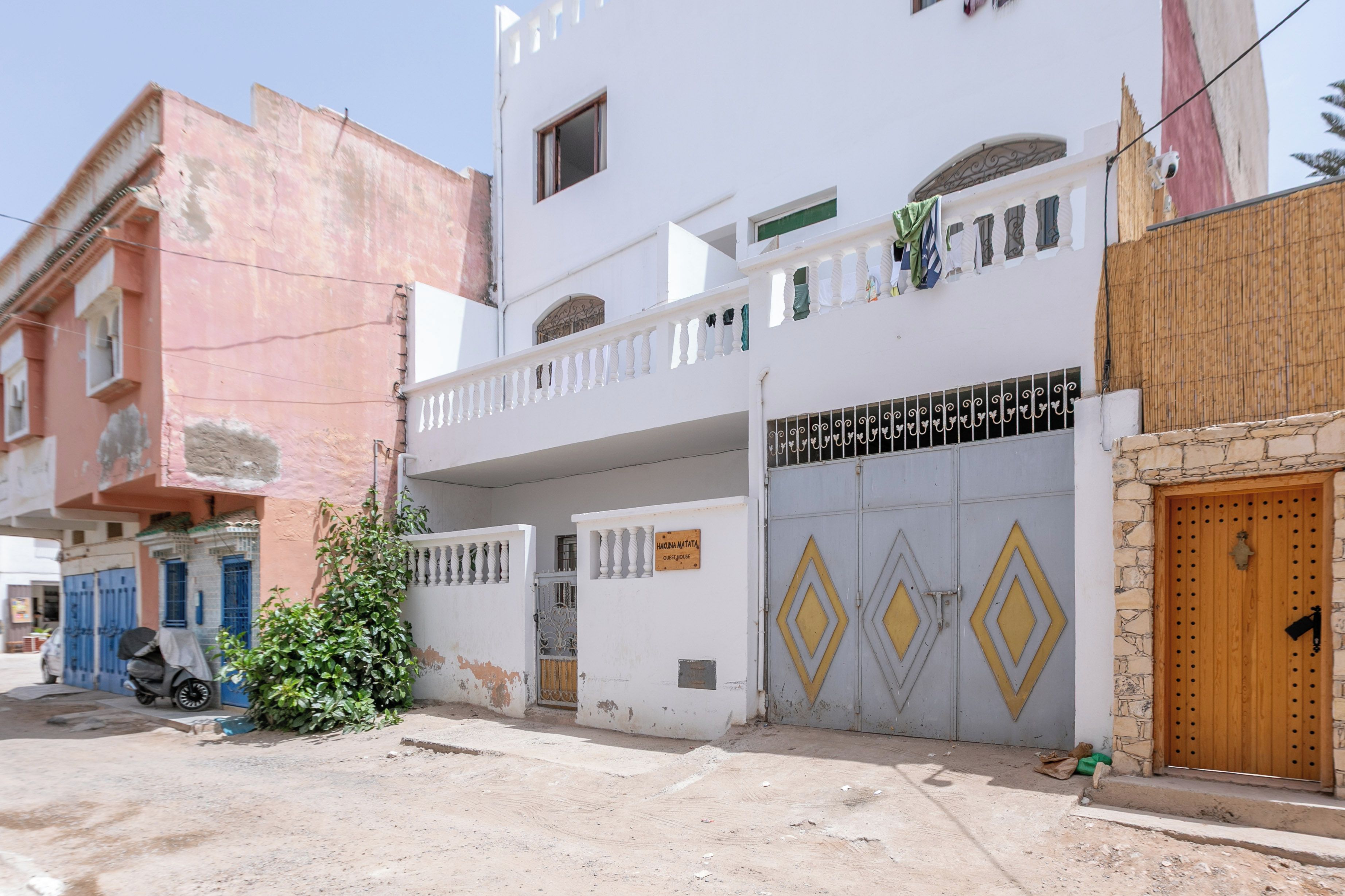 A two-story building with a balcony, a gated entrance, and a sign indicating it's a guesthouse.