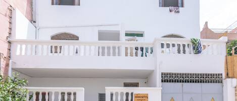 Ein zweistöckiges Gebäude mit einem Balkon, einem Tor mit einem Schild und einem schmiedeeisernen Tor.