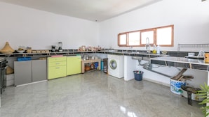 A spacious kitchen with a central island, a washing machine, and a sink. - Hakuna Matata Guest House (TAMRAGHT)
