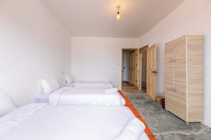 Habitación de hotel con dos camas, un armario y un pasillo que lleva a otra habitación.