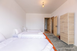 Habitación de hotel con dos camas, un armario y un pasillo que lleva a otra habitación.