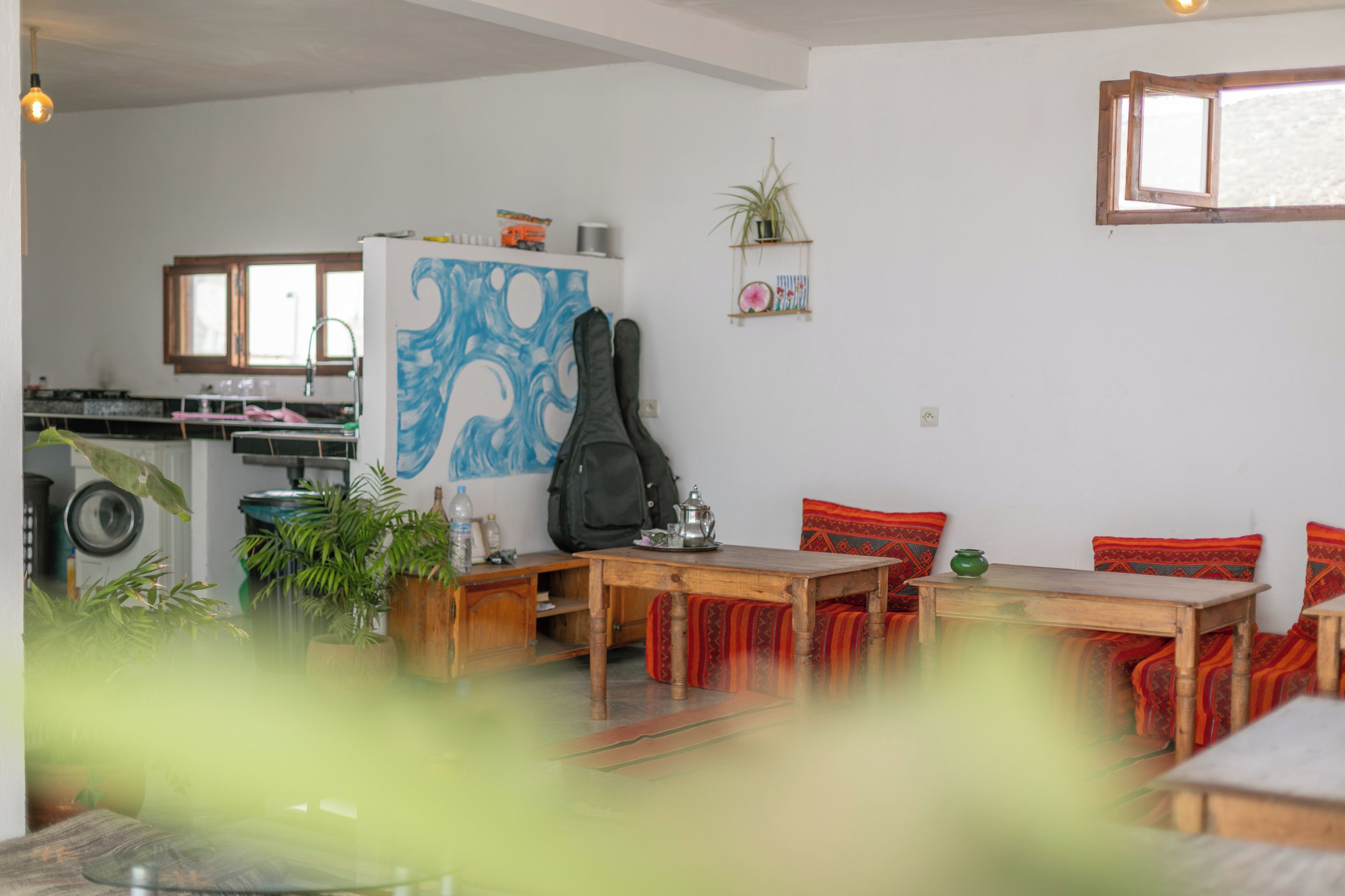 A dining area with a wooden table and chairs, a refrigerator with a blue abstract design, and a kitchen in the background.