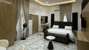 Una habitación de hotel moderna con una cama, mesita de noche, silla y un ventilador.