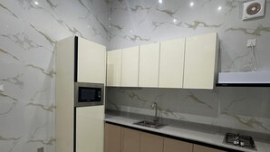 Una cocina con paredes de mármol, microondas, fregadero y estufa a gas.
