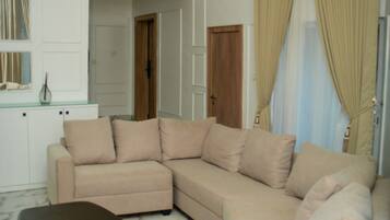 A living room with a beige sectional sofa, a small brown ottoman, and a white cabinet.