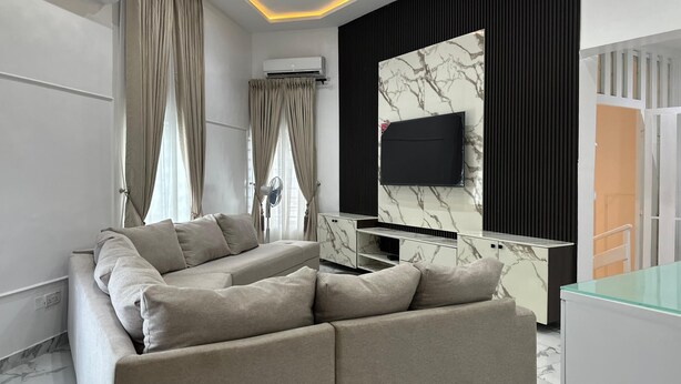 Una sala de estar moderna con un sofá seccional, un televisor de pantalla plana y una pared con estampado de mármol.