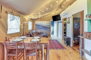 Un interior acogedor con comedor, sofá, chimenea y un ventanal con cortinas.