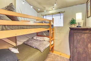 Habitación con literas, una escalera, un escritorio con lámpara y una ventana con cortinas.