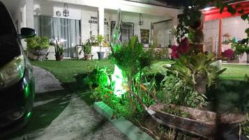 Imóvel residencial com entrada por rampa, um carro e diversos vasos de plantas.
