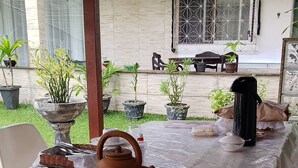 A covered outdoor dining area with a table set for tea, surrounded by potted plants and a building with a sign reading 'POUSADA GUIMARÃES'. - Pousada Guimarães muriqui  (Mangaratiba)