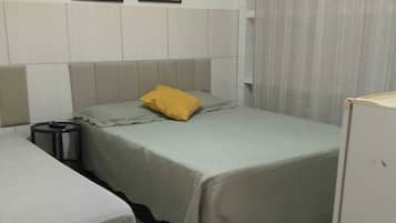Quarto com uma cama, mesa de cabeceira, armário pequeno e três quadros florais na parede.