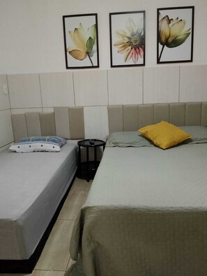 Ein Hotelzimmer mit zwei Betten, einem Nachttisch und einem an der Wand befestigten Fernseher.