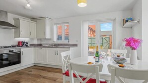 Una cocina moderna con armarios blancos, una estufa a gas y un comedor con una mesa dispuesta para dos personas.