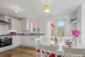 Una cocina moderna con armarios blancos, una estufa a gas y un comedor con una mesa dispuesta para dos personas.