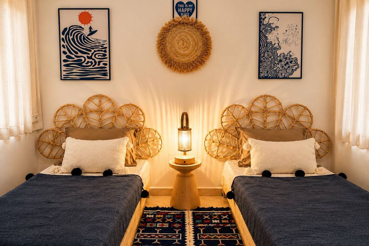 A room with two beds, a central lamp, and wall art.