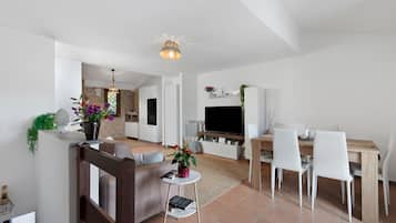 Ein zeitgemäßer Wohnraum mit Essbereich, Küche und einem an der Wand befestigten Fernseher.