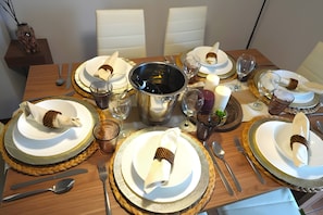 A dining table set with plates, glasses, cutlery, and a centerpiece.