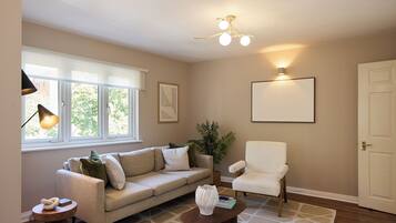 A living room with a sofa, armchair, coffee table, lamp, plant, and a framed picture on the wall.