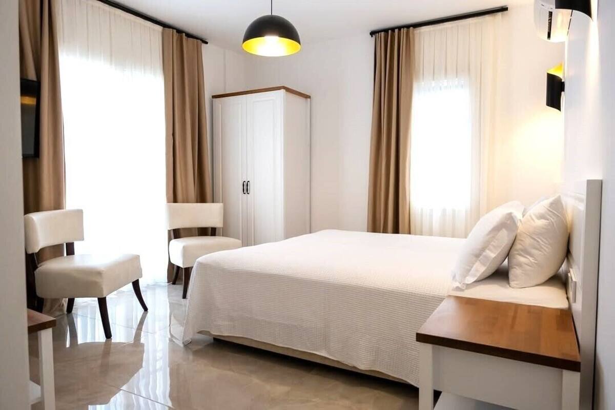Quarto de hotel com cama, cadeira, guarda-roupa e mesa de cabeceira.